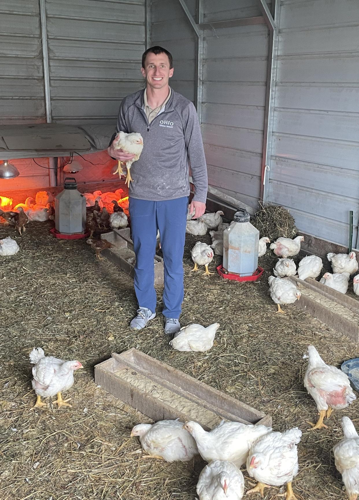Adam Paynter, standing outside of his home in Shelby, holds a broiler chicken raised for meat. He began with $100 and 100 chickens as a teen, and now has 700 broiler meat chickens, laying hens and 65 Thanksgiving turkeys.