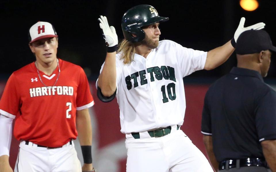 In this Friday, June 1, 2018, photo, Stetson player Brooks Wilson (10) celebrates in front of Hartford player jackson Olson (2) after Wilson hit an RBI double during  an NCAA Div. I Regional baseball game in Deland, Fla. Stetson, the tiny Florida college that produced two-time AL Cy Young Award winner Corey Kluber and 2014 NL Rookie of the Year Jacob deGrom, is headed to the Super Regionals for the first time.  (Stephen M. Dowell/Orlando Sentinel via AP)