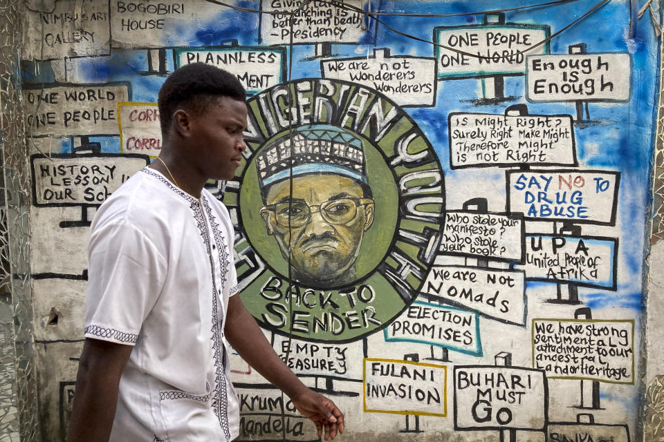 A man walks past an artist's mural, painted for a previous election and showing incumbent President Muhammadu Buhari, in Lagos, Nigeria Friday, Feb. 24, 2023. Nigerian voters are heading to the polls Saturday to select a new president following the second and final term of incumbent President Muhammadu Buhari. (AP Photo/Ben Curtis)