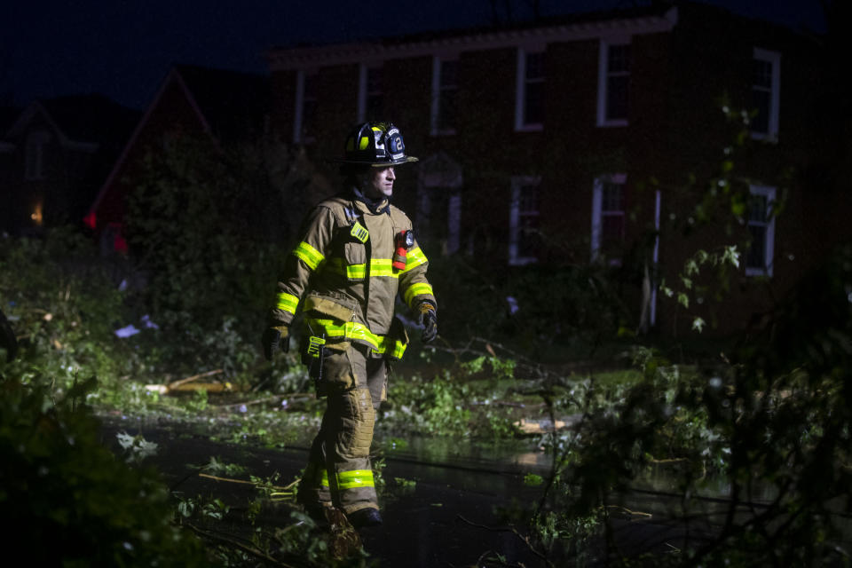 A firefighter walks through debris from a strong storm that ripped through the Great Neck area of Virginia Beach, Va., on Sunday, April 30, 2023. (Kendall Warner/The Virginian-Pilot via AP)