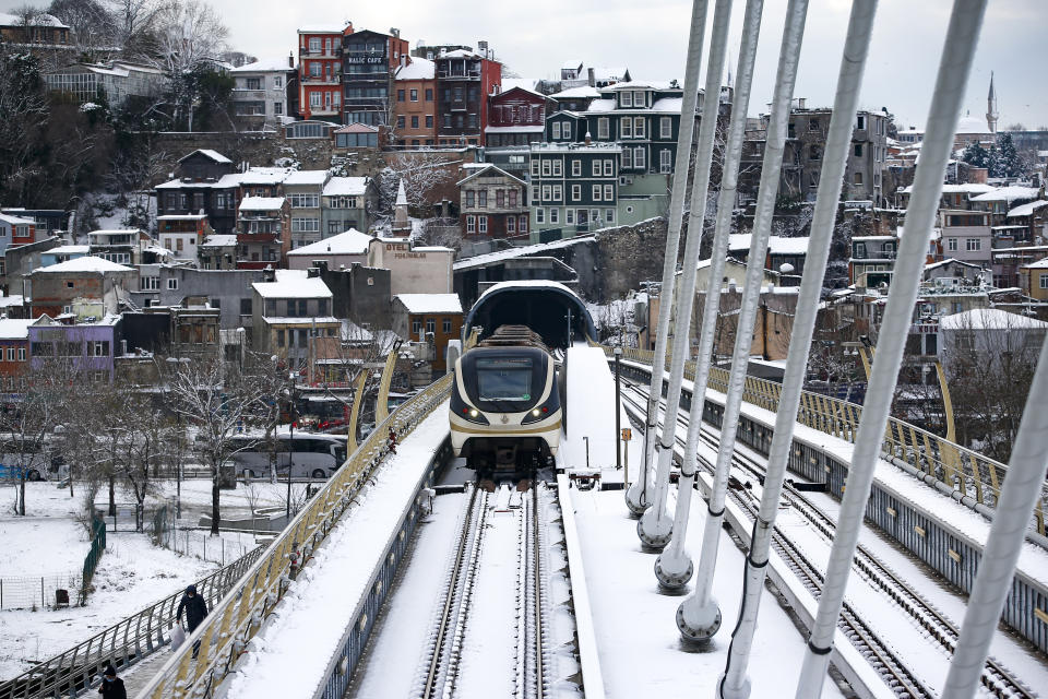 People walk over the Golden Horn bridge at Istanbul, Tuesday, Jan. 25, 2022. Rescue crews in Istanbul and Athens on Tuesday cleared roads that had come to a standstill after a massive cold front and snowstorms hit much of Turkey and Greece, leaving countless people and vehicles in both cities stranded overnight in freezing conditions.(AP Photo/Emrah Gurel)