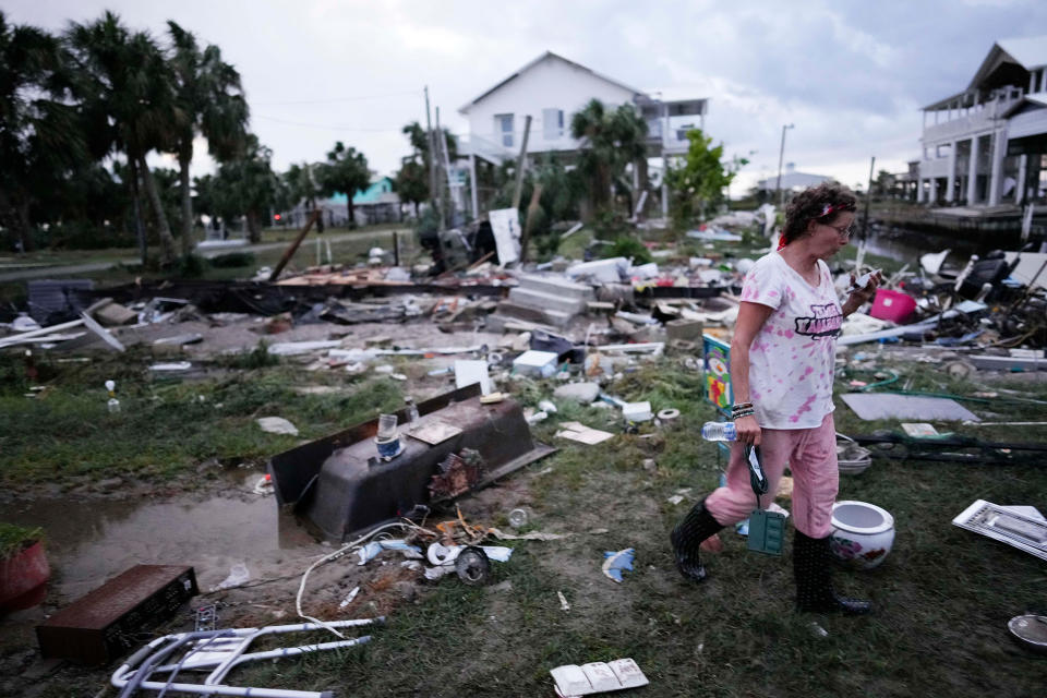 A woman walks amidst debris strewn across the yard where her mother's home had stood, as she searches for anything salvageable in Horseshoe Beach, Fla., after the passage of Hurricane Idalia, on Aug. 30, 2023.  (Rebecca Blackwell / AP)