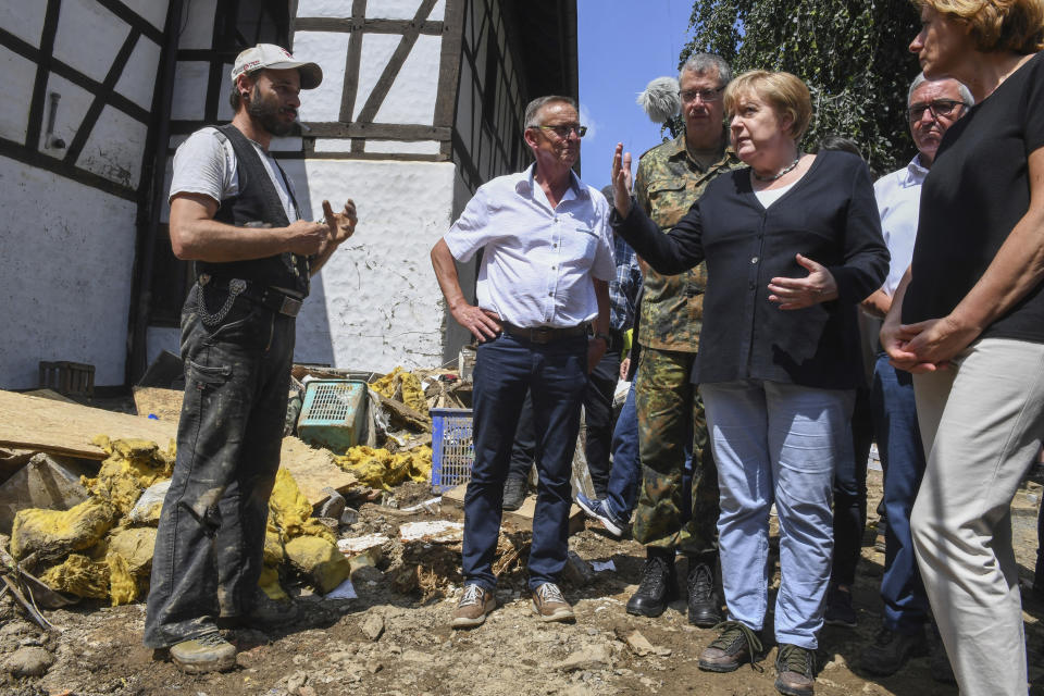 German Chancellor Angela Merkel, front second right, gestures as she and the Governor of the German state of Rhineland-Palatinate, Malu Dreyer, front right, talk to a resident in Schuld, western Germany, Sunday, July 18, 2021 during their visit in the flood-ravaged areas to survey the damage and meet survivors. After days of extreme downpours causing devastating floods in Germany and other parts of western Europe the death toll has risen. (Christof Stache/Pool Photo via AP)