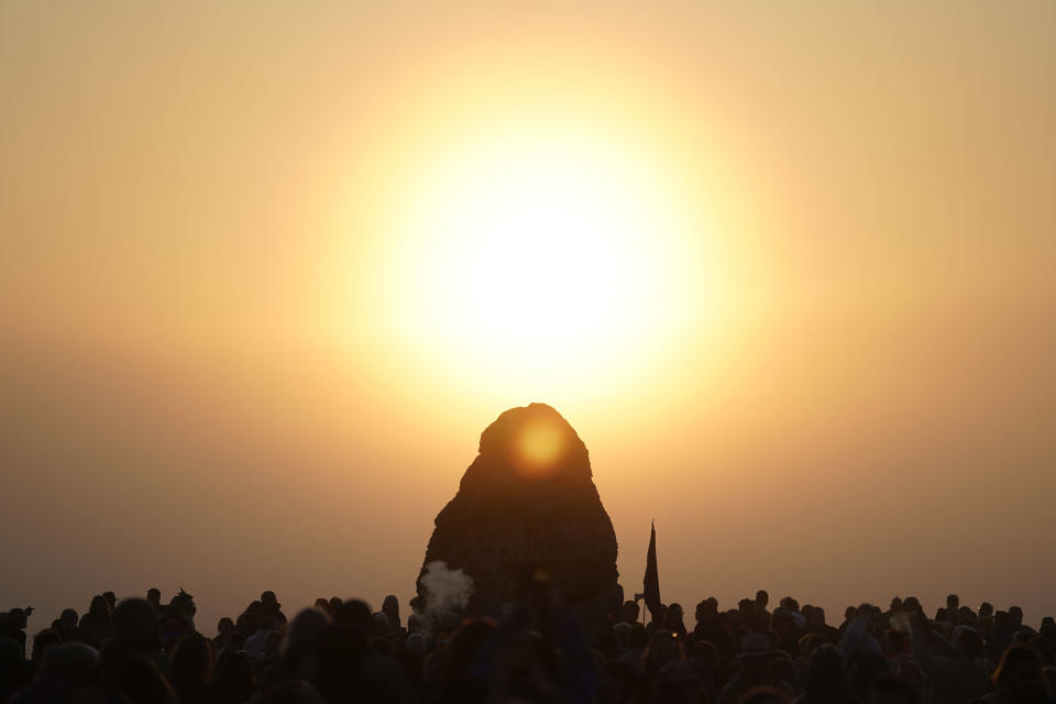 People gather around the Heel Stone during sunrise as they take part in the Summer Solstice at Stonehenge in Wiltshire, England Wednesday, June 21, 2023. (Andrew Matthews/PA via AP)