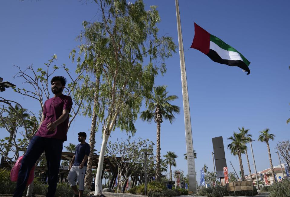 People pass by the UAE national flag flies at half-staff after the announcement of the Emirates president's death, in Dubai, United Arab Emirates, Friday, May 13, 2022. Sheikh Khalifa died Friday, May 13, 2022, the government's state-run news agency announced in a brief statement. He was 73. (AP Photo/Kamran Jebreili)