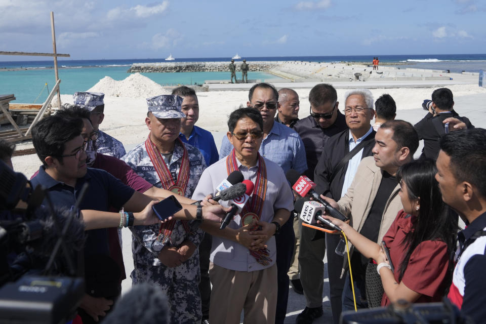 National Security Adviser Eduardo Ano, center, answers questions from reporters at the Philippine-occupied Thitu island, locally called Pag-asa island, on Friday, Dec. 1, 2023 at the disputed South China Sea. The Philippine coast guard inaugurated a new monitoring base Friday on a remote island occupied by Filipino forces in the disputed South China Sea as Manila ramps up efforts to counter China's increasingly aggressive actions in the strategic waterway. (AP Photo/Aaron Favila)