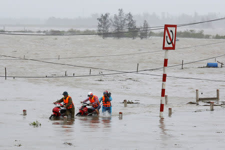 People recover motorbikes from a flooded fields while the Doksuri storm hits in Ha Tinh province, Vietnam September 15, 2017. REUTERS/Kham