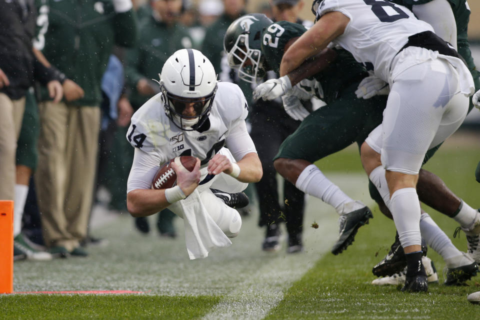 Penn State quarterback Sean Clifford, left, dives for a first down against Michigan State's Shakur Brown (29) during the first quarter of an NCAA college football game, Saturday, Oct. 26, 2019, in East Lansing, Mich. (AP Photo/Al Goldis)