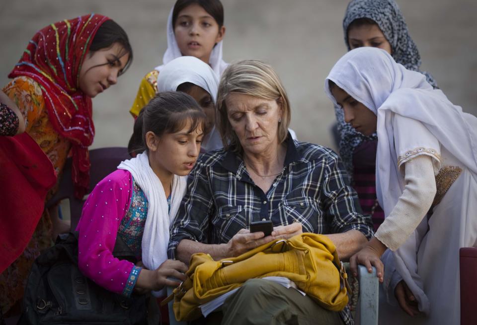 ARCHIVO - En esta imagen del sábado 1 de octubre de 2011, la corresponsal regional especial de Associated Press para Afganistán y Pakistán, Kathy Gannon, sentada con varias niñas en una escuela de Kandahar, Afganistán. Una corte en Kabul anunció el 23 de julio de 2014 que el policía afgano acusado de matar a la fotógrafa de Associated Press Anja Niedringhaus y herir a la veterana corresponsal de AP Kathy Gannon había sido condenado a muerte. (AP Foto/Anja Niedringhaus, Archivo)