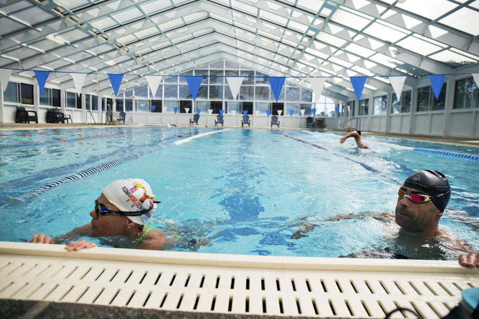 In this undated photo, three-time Ironman world champion Mirinda Carfrae, left, and her husband, elite triathlete Tim O'Donnell, finish up a training swim at a health club in Lawrence, Kan. The couple is finishing preparations for next month's triathlon world championships in Kona, Hawaii, while juggling their new life with 1-year-old daughter Isabelle. (Talbot Cox via AP)