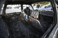 A man looks in a burnt out car after multiple rocket system shelling by Armenian forces in Barda, Azerbaijan, Wednesday, Oct. 28, 2020. The Azerbaijani Defense Ministry rejected all the accusations and in turn accused Armenian forces of using the Smerch multiple rocket system to fire at the Azerbaijani towns of Terter and Barda. The strike on Barda killed more than 20 people and wounded 60, Azerbaijani officials said. (AP Photo/Aziz Karimov)