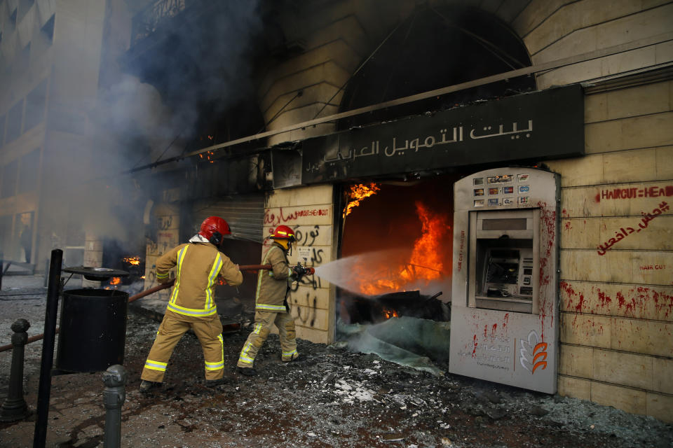 FILE - Firefighters hose the branch of the Credit Libanais Bank that was burnt by anti-government protesters in the northern city of Tripoli, Lebanon, Tuesday, April 28, 2020. Four years into Lebanon's historic economic meltdown, Lebanon's elites are pushing an economic recovery plan that would sidestep critical reforms demanded by the International Monetary Fund. (AP Photo/Bilal Hussein, File)