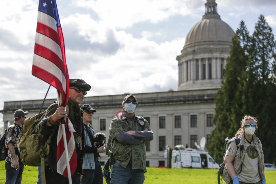 A protester wearing a mask holds a US flag during a demonstration against Washington state's stay-home order at the state capitol in Olympia, Washington