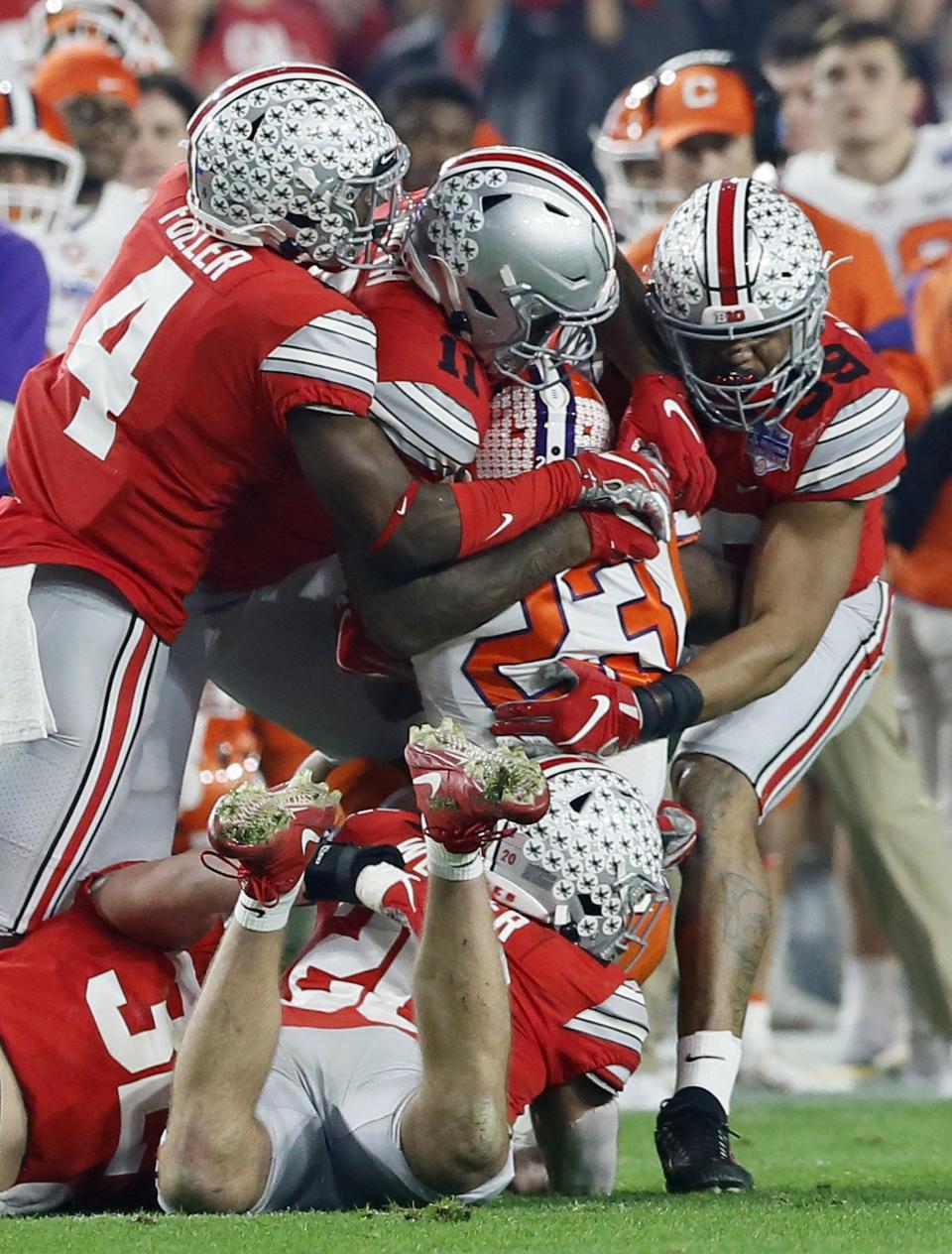 A herd of Ohio State Buckeyes defenders, including defensive end Tyreke Smith (11), tackle Clemson Tigers running back Lyn-J Dixon (23) during the first quarter of the College Football Playoff Semifinal at the PlayStation Fiesta Bowl at State Farm Stadium in Glendale, Ariz. on Saturday, Dec. 28, 2019. [Adam Cairns/Dispatch]