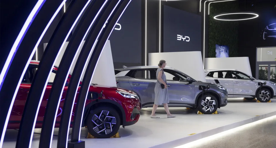 Woman looks at cars in a BYD display room.