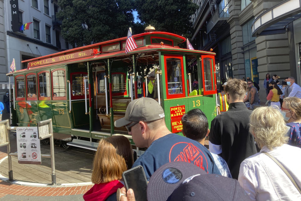 People line up to board a cable car at the Powell Street turnaround plaza in San Francisco on Monday, Aug. 2, 2021. San Francisco's iconic cable cars are rolling again after being sidelined by the pandemic for months. People were already forming long lines to ride the cable cars, which will offer free rides the month of August. (AP Photo/Olga Rodriguez)