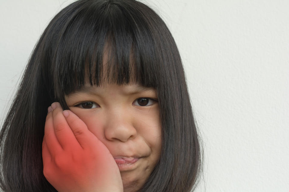 TMD and TMJ healthcare concept: Temporomandibular Joint and Muscle Disorder. Asia child kid girl hand on cheek face as suffering from facial pain, mumps or toothache