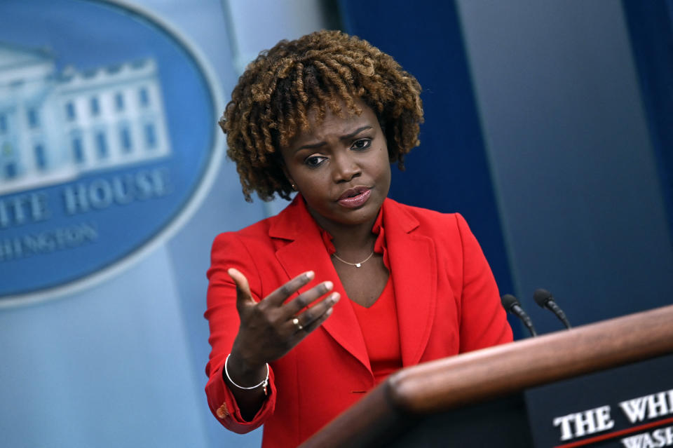 Karine Jean-Pierre, wearing bright red, at the podium.