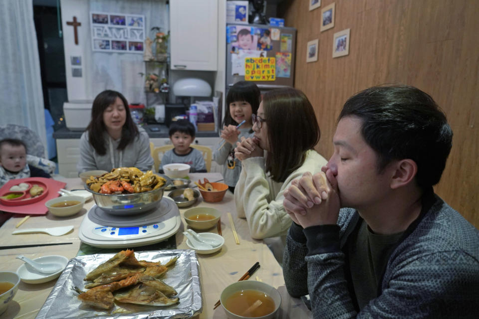 Mike Hui, right, prays before the Chinese New Year dinner at home in Hong Kong on Feb. 10, 2021. Until early April, Hui was a photojournalist for the Apple Daily, a pro-democracy newspaper that shut down following the arrest of five top editors and executives and the freezing of its assets under a national security law that China's ruling Communist Party imposed on Hong Kong as part of the crackdown. (AP Photo/Kin Cheung)