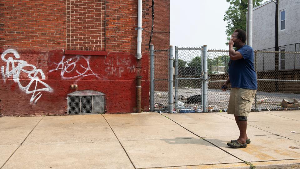 Lifelong Camden resident Christoff Lindsey reflects in front a vacant school in his neighborhood, where Lindsey once played basketball, that is now littered with items such as spent syringes and human waste.