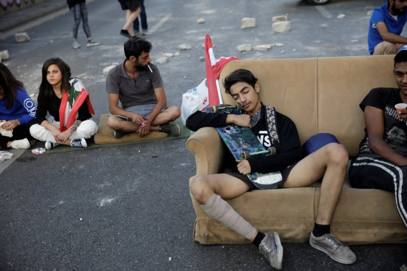 A demonstrator rests on a sofa blocking a street during ongoing anti-government protests in Beirut