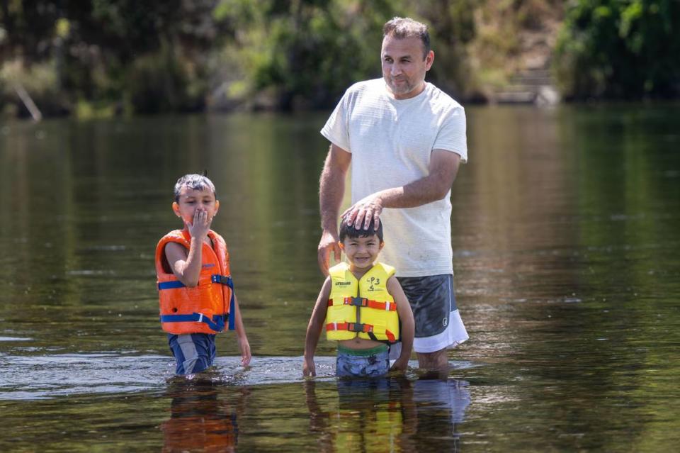 Noorullah Jambi, of Sacramento, enjoys the cold water with his son’s Shahab, 5, and Jason, 3, on the American River at River Bend Park in Carmichael on Thursday, June 27, 2024. Weather forecast warns of triple digits temperatures starting July 1.