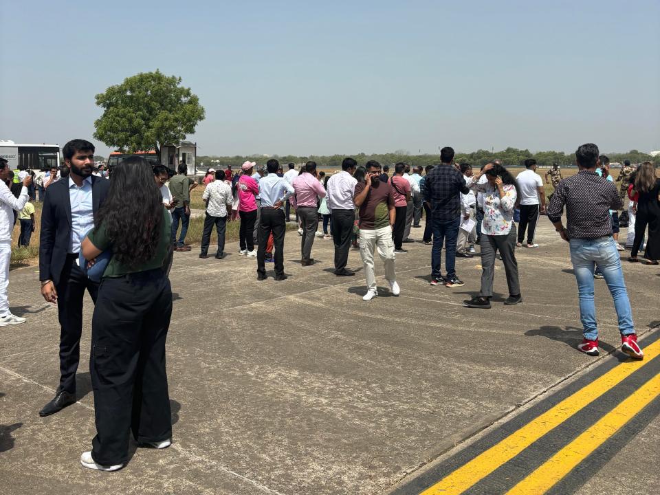 Passengers take phone calls and wait on the runway at Ahmedabad Airport following a bomb threat scare in June 2024