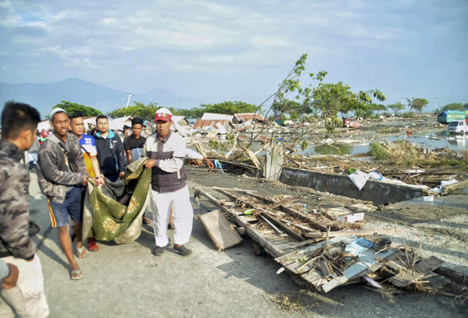 <p> People carry the body of a tsunami victim in Palu, Central Sulawesi, Indonesia, Saturday, Sept. 29, 2018. A powerful earthquake rocked the Indonesian island of Sulawesi on Friday, triggering a 3-meter-tall (10-foot-tall) tsunami that an official said swept away houses in at least two cities. (AP Photo/Rifki) </p>