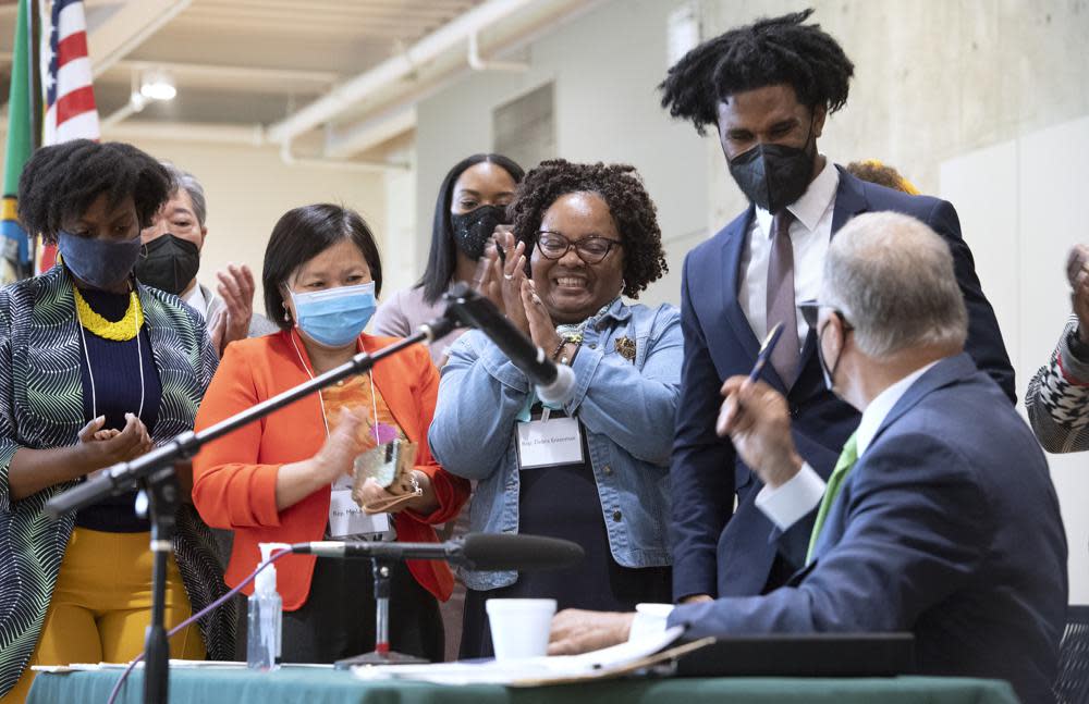 (Left to right ) Washington state representatives Jamila Taylor, My-Linh Thai and Debra Entenman applaud as Rep. Jesse Johnson accepts a pen from Gov. Jay Inslee after the governor signed 12 bills related to police accountability during ceremonies on May 18, 2021 at the Eastside Community Center in Tacoma. Recent, Tacoma city officials agreed to pay $3.1 million to the family of a Black man whom police fatally shot during a traffic stop in 2019. (Tony Overman/The News Tribune via AP)