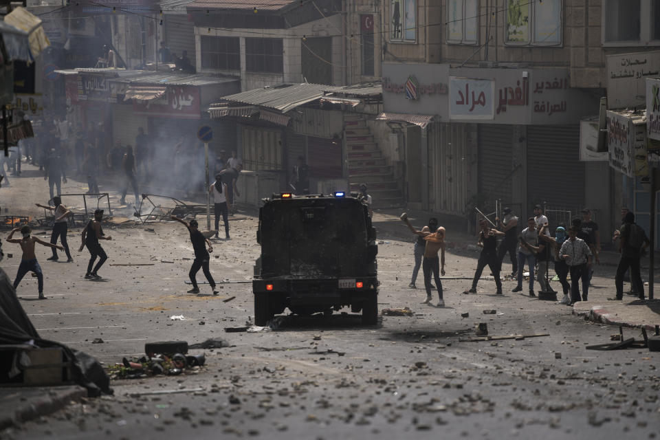 Palestinians clash with Palestinian security forces following an arrest raid against local militants, in the West Bank city of Nablus Tuesday, Sept. 20, 2022. Palestinian security forces on Tuesday exchanged fire with militants in the center of the West Bank's second-largest city, as angry residents pelted an armored jeep with objects and chased it away. One man was reported dead. The incident, sparked by an arrest raid against local militants, marked a rare case of deadly internal Palestinian fighting in the occupied West Bank. (AP Photo/Nasser Nasser)