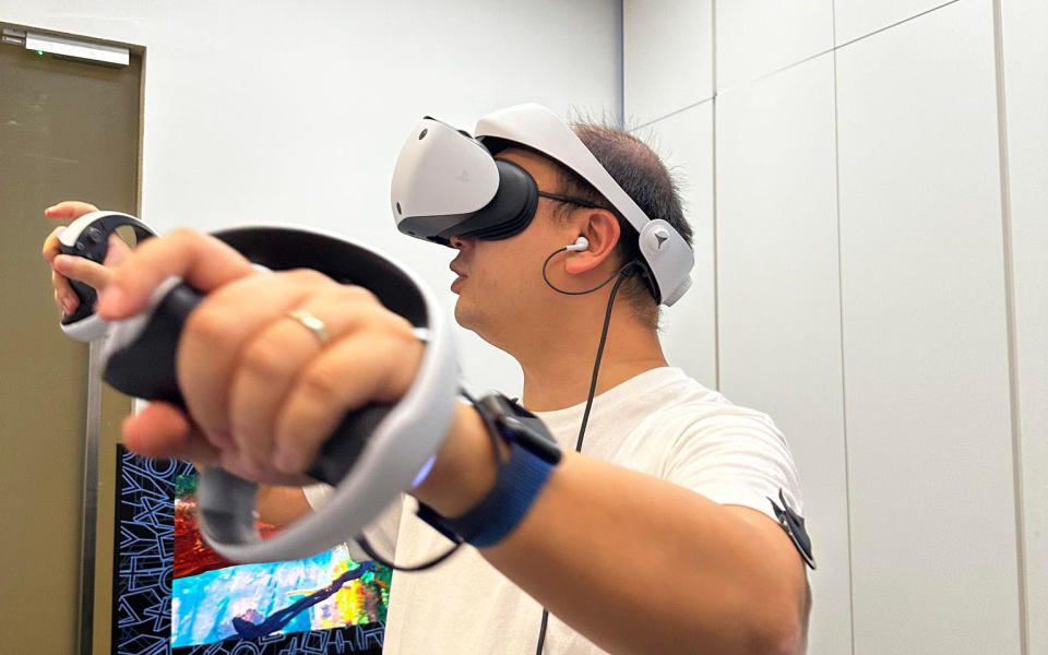 A man using a white PlayStation virtual reality headset to play games
