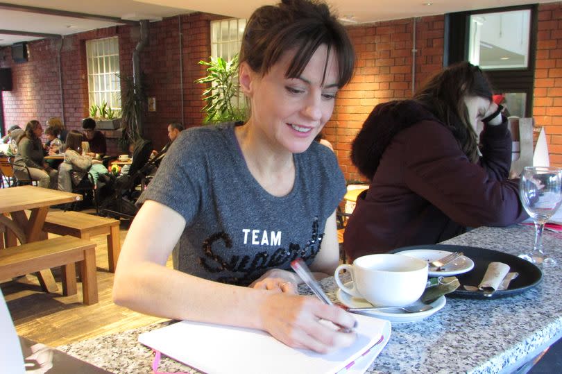 Woman writes while sat in a cafe