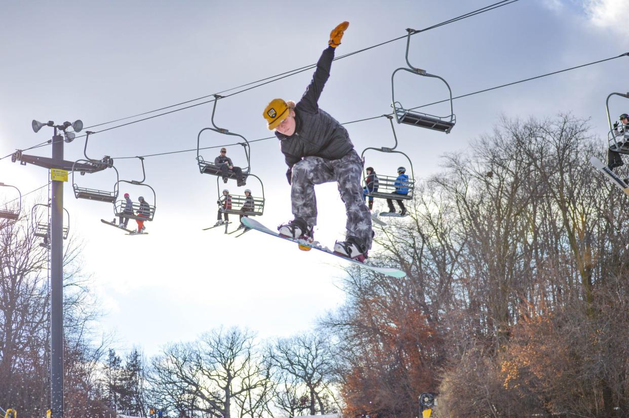 Chairlifts can be seen in the background as a snowboarder makes a jump at Seven Oaks recreation area in Boone, Iowa.