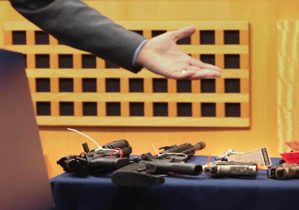 El comisionado Ken Russell señala 12 de las 167 armas recolectadas durante una rueda de prensa.