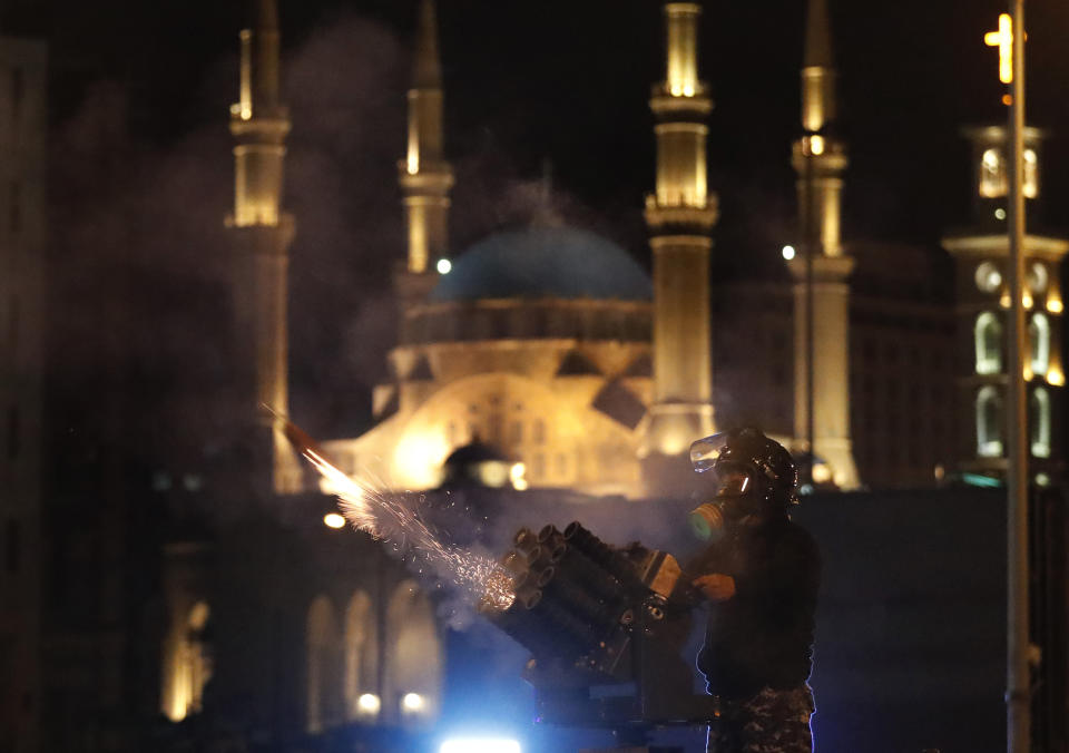 A riot police officer fires tear gas from a launcher against anti-government protesters trying to enter parliament square in downtown Beirut, Lebanon, Saturday, Dec. 14, 2019. The recent clashes marked some of the worst in the capital since demonstrations began two months ago. The rise in tensions comes as politicians have failed to agree on forming a new government. (AP Photo/Hussein Malla)