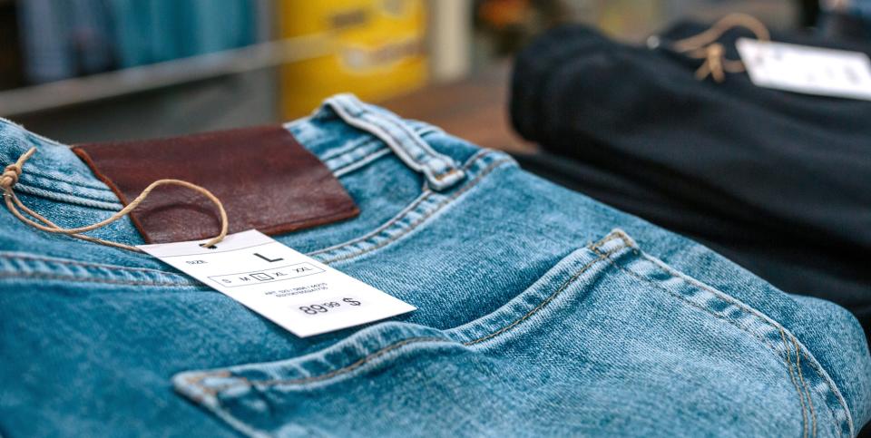 Folded pairs of jeans on display at a store, each with a size label attached. No visible people in the image