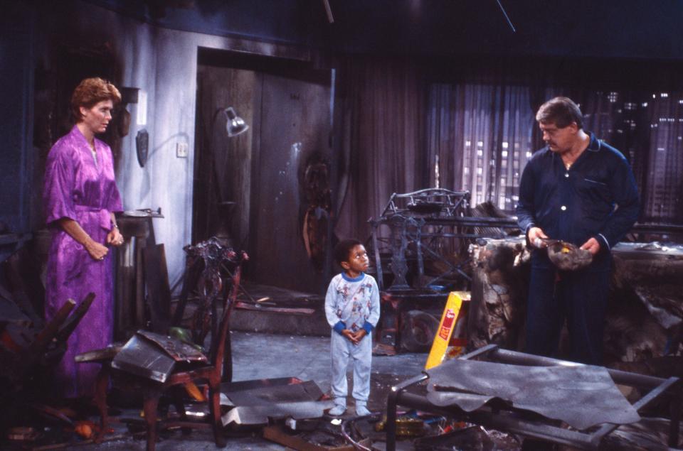 Webster standing in burned down apartment with his parents looking shocked