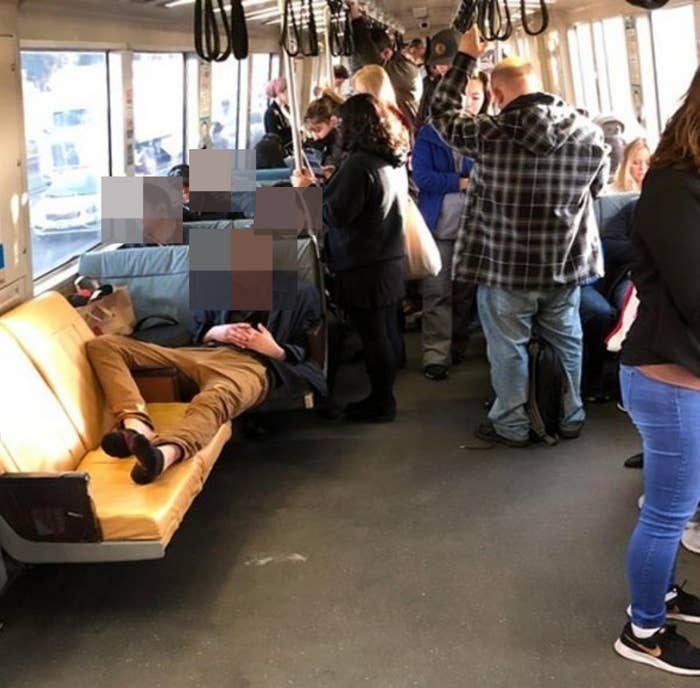 A man with his feet on a bench, blocking people from sitting