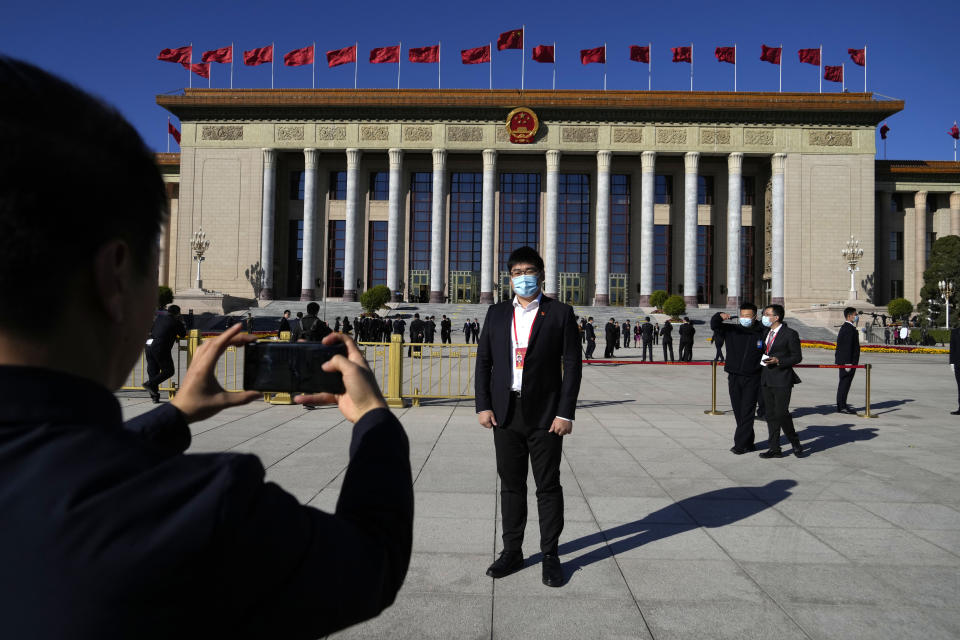 An attendee poses for a photo in front of the Great Hall of the People ahead of the closing ceremony of the 20th National Congress of China's ruling Communist Party in Beijing, Saturday, Oct. 22, 2022. (AP Photo/Ng Han Guan)