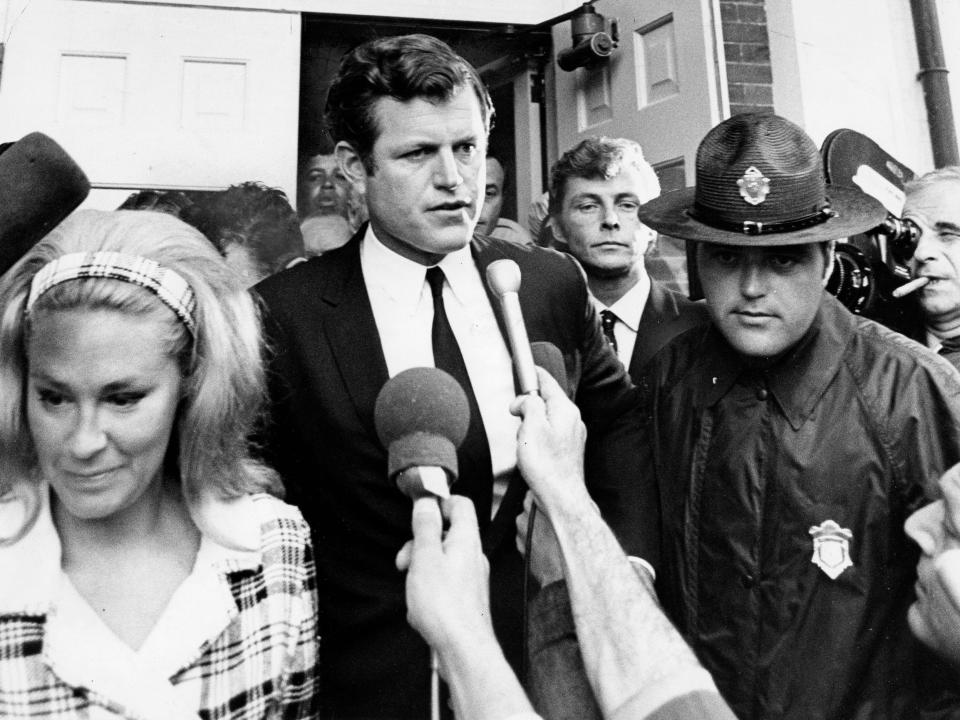 Sen. Edward M. Kennedy leaves a courthouse in 1969 escorted by security as reporters put microphones toward him