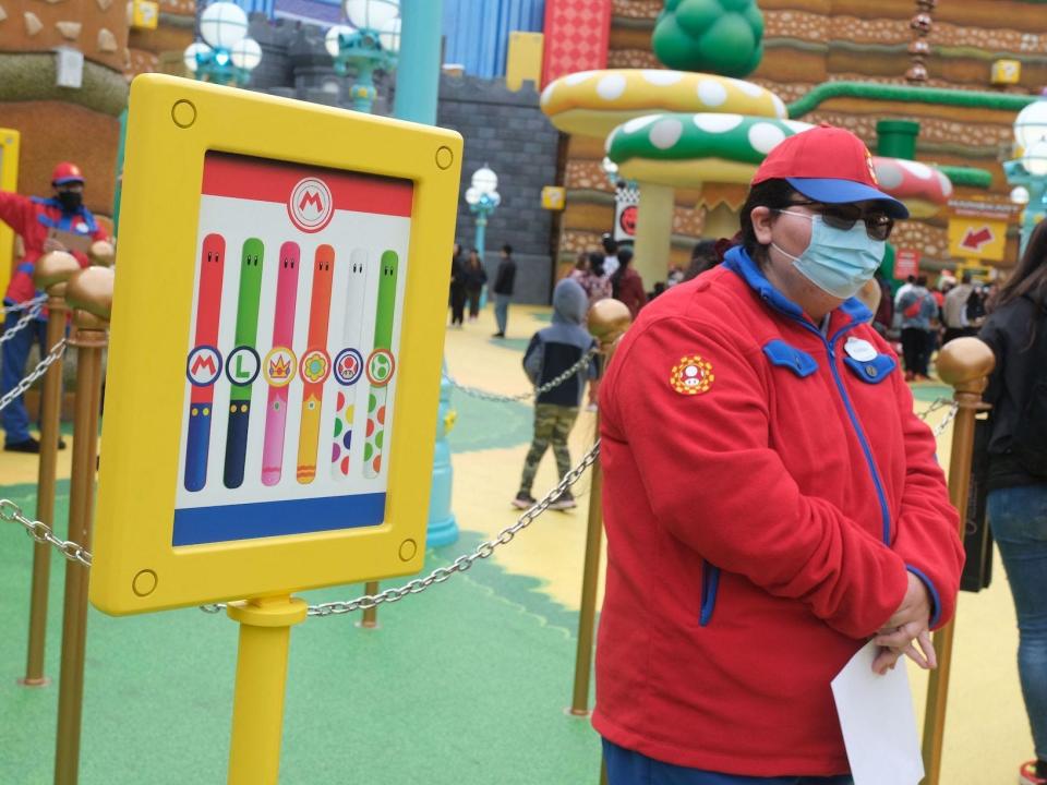 A staff member stands by a poster of power-up bands during a preview of Super Nintendo World at Universal Studios in Los Angeles, California, on January 13, 2023.