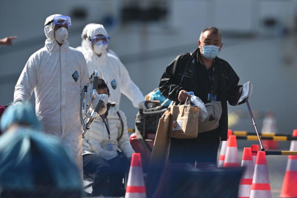 Health workers help passengers disembark from the Diamond Princess cruise ship at Daikoku pier in Yokohama, Japan, on Feb. 21, 2020. | Philip Fong—AFP/Getty Images