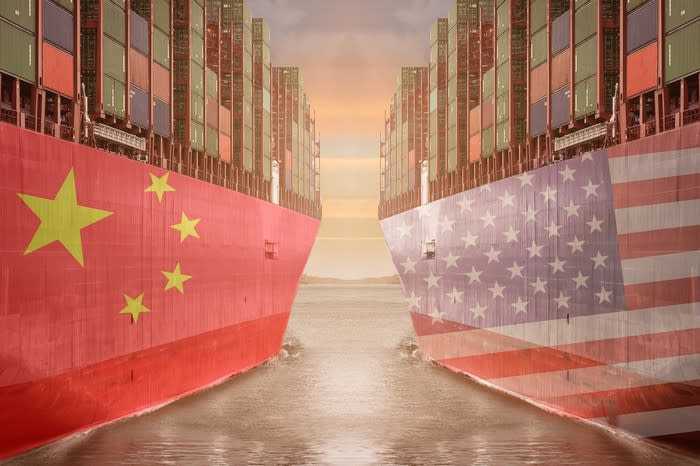 Two cargo ships next to each other, one with the Chinese flag and the other with the American flag.