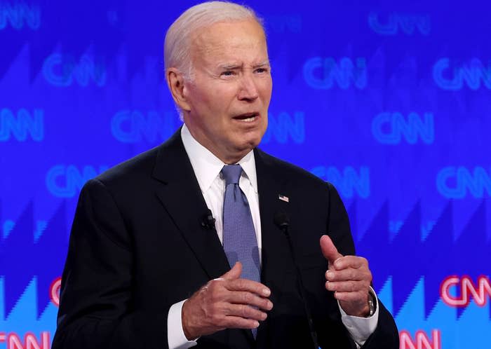 Joe Biden speaks at a CNN event, standing in front of a CNN-branded backdrop, wearing a suit and tie