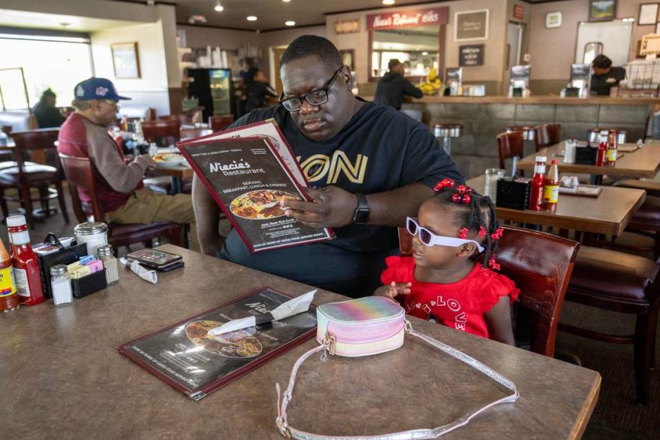 D’Mari Harding of Baton Rouge, Louisiana, looks over the menu for himself and his daughter, Grace Harding, 2, during a visit for breakfast at Niecie’s Restaurant. Tammy Ljungblad/Tljungblad@kcstar.com