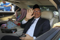 Anwar Ibrahim, right, and his wife Wan Azizah Ismail sit in a car wave to their supporters as they arrive to the National Palace to meet the king in Kuala Lumpur, Malaysia, Wednesday, Feb. 26, 2020. Malaysia's king held unusual consultations with lawmakers for a second day Wednesday to resolve a political vacuum caused by the abrupt collapse of the ruling coalition and the resignation of Prime Minister Mahathir Mohamad. (AP Photo)