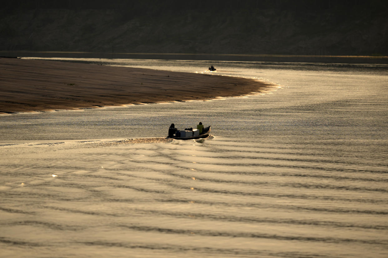 People move down the Middle Jurua river, Amazonia, Brazil, Friday, Sept. 2, 2022. The pirarucus are then taken from the lakes to a large boat by the Jurua River. There they are gutted, a task that is mostly done by women, and put on ice. (AP Photo/Jorge Saenz)