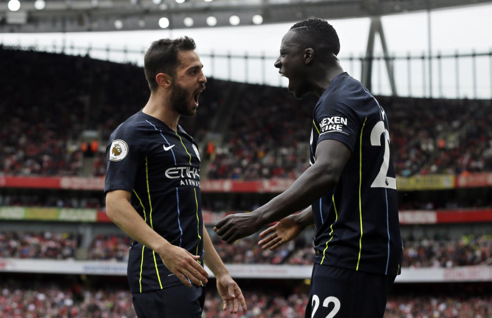 Manchester City's Bernardo Silva celebrates with teammate Benjamin Mendy, right, after scoring his side's second goal during the English Premier League soccer match between Arsenal and Manchester City at the Emirates stadium in London, England, Sunday, Aug. 12, 2018. (AP Photo/Tim Ireland)