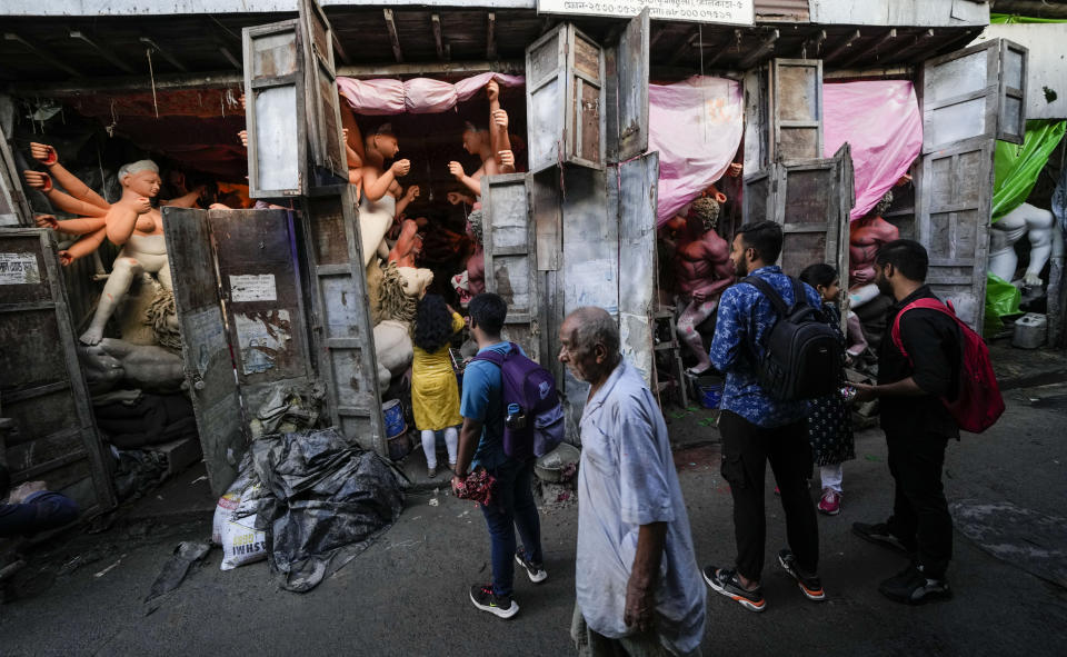 People walk past studios filled with idols of Hindu goddess Durga ahead of Durga Puja festival at Kumortuli, the potters' place, in Kolkata, India, Sept. 19, 2022. The five-day festival commemorates the slaying of a demon king by goddess Durga, marking the triumph of good over evil. (AP Photo/Bikas Das)