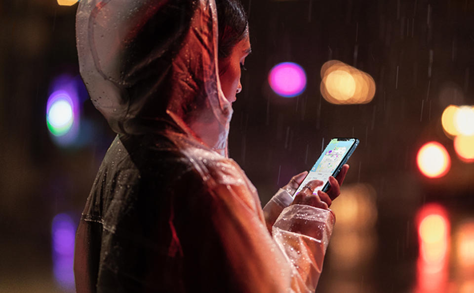 A woman uses an iPhone XR in the rain.